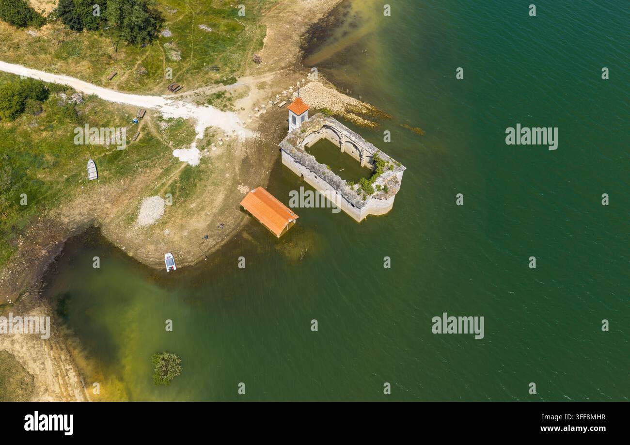 Luftbild der versunkenen Kirche St. Nikolaus, teilweise im Mavrovo-See versunken, mit grasbewachsenen Ufern und einer kleinen Struktur in Mavrovo, Gemeinde Stockfoto