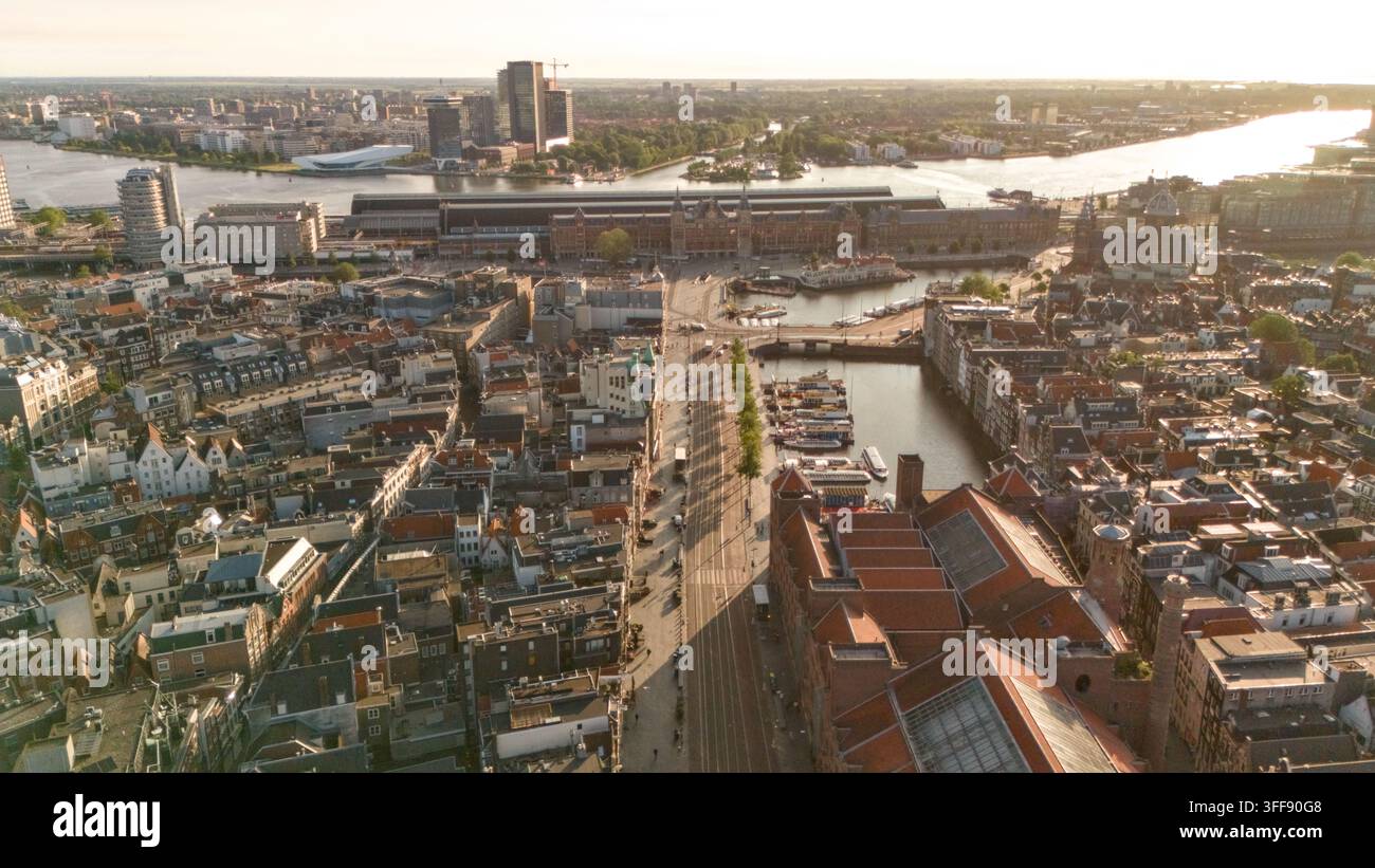 Luftbild von Amsterdam mit dem Hauptbahnhof, dichten historischen Dächern, Straßenbahnschienen, Wasserwegen, Booten und modernen Gebäuden im gesamten Stadtzentrum. Stockfoto