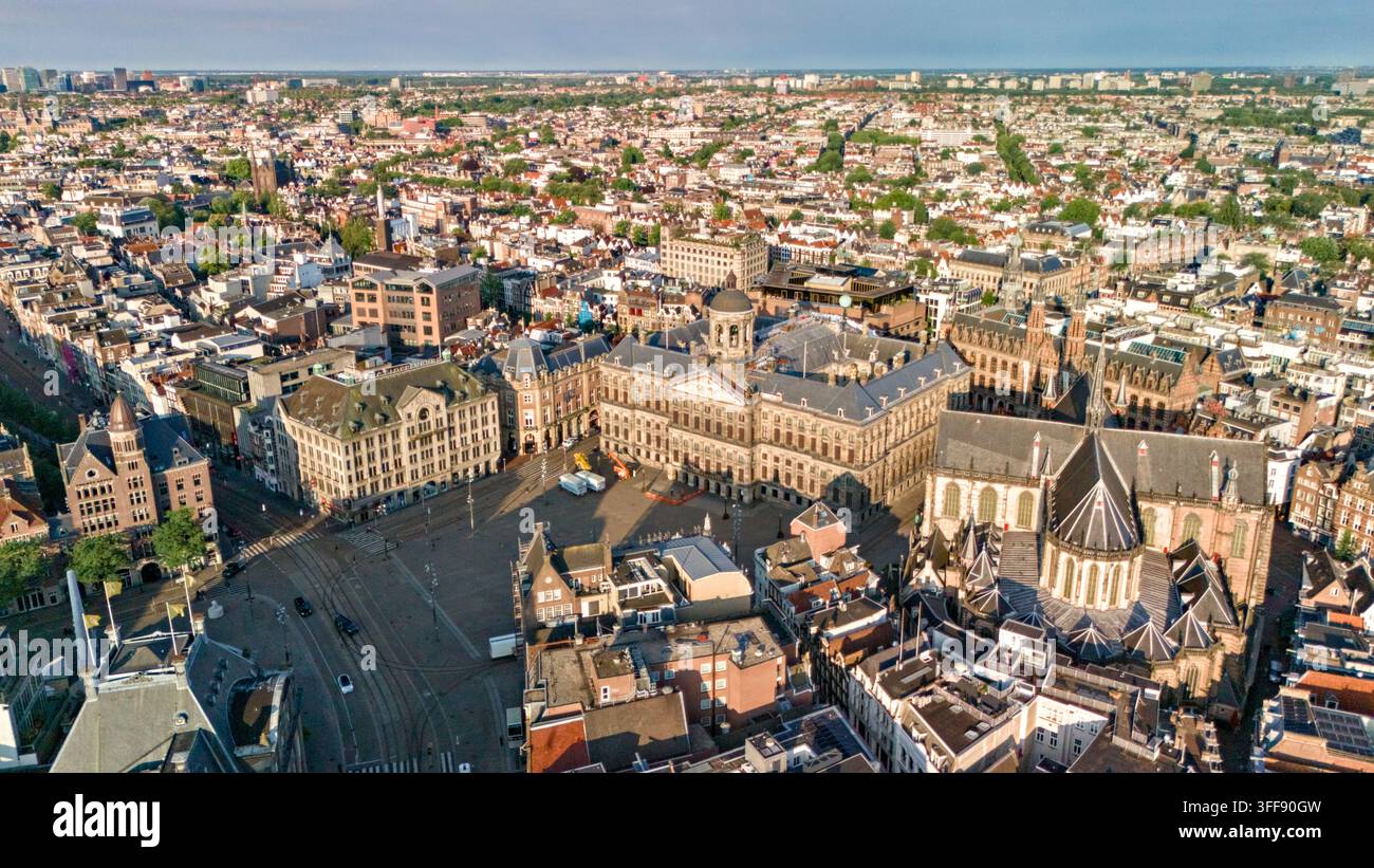 Luftbild über den Dam-Platz von Amsterdam, das Königspalast, Nieuwe Kerk, historische Dächer, umliegende Straßen und dichte städtische Architektur zeigt. Stockfoto