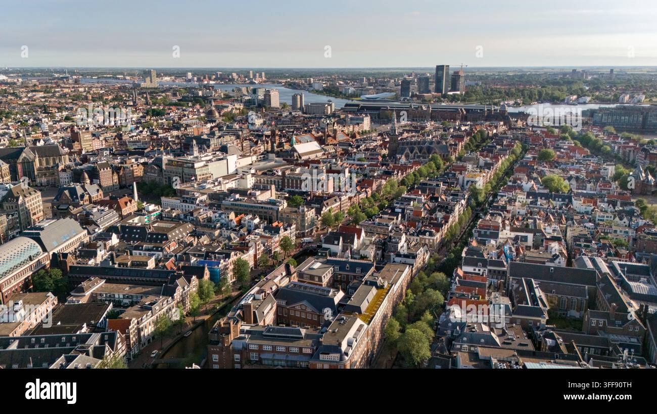Luftaufnahme historischer Dächer und Kanäle mit dem Amsterdam Centraal Bahnhof in der Ferne, Amsterdam, Niederlande. Stockfoto