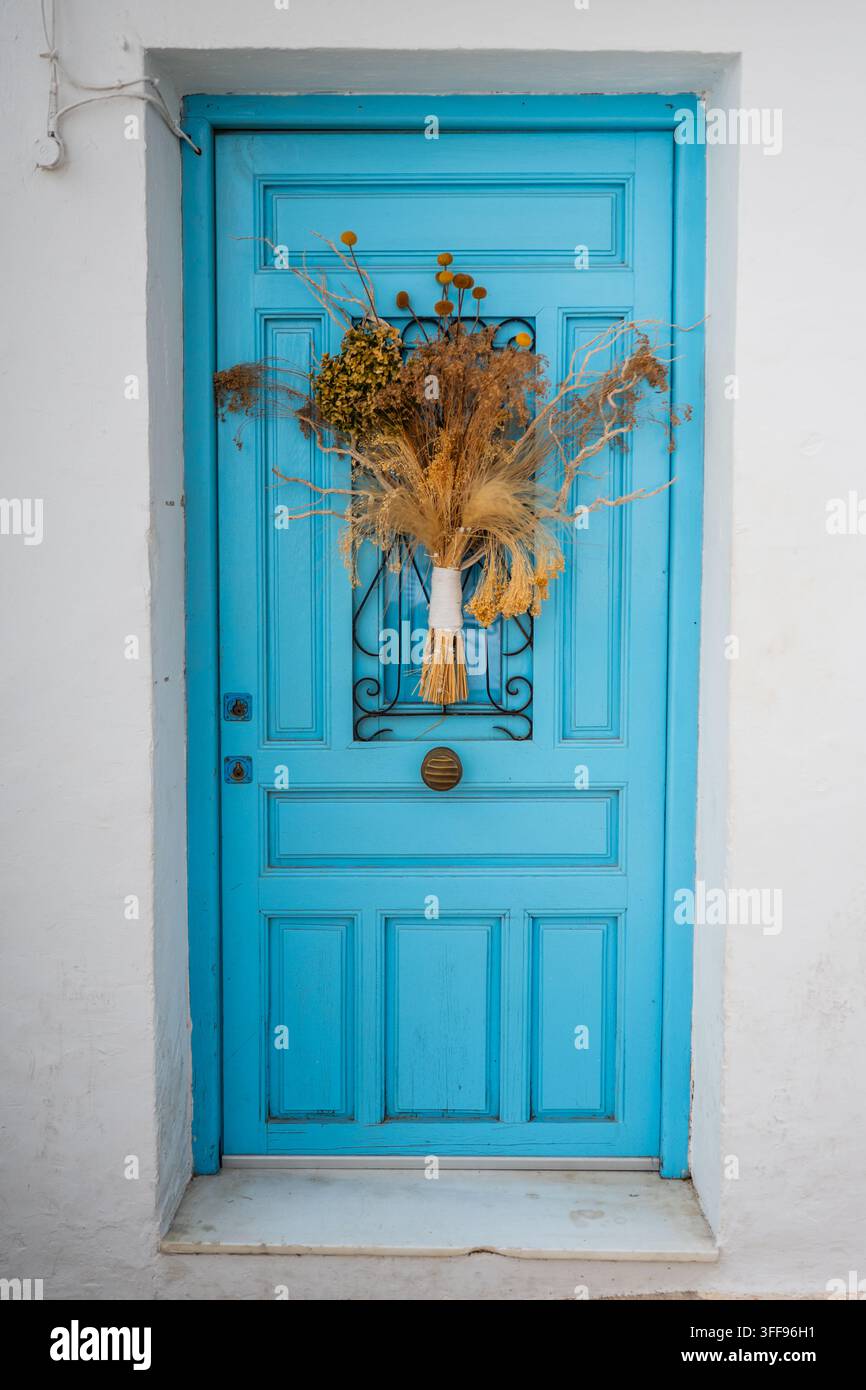Lebendige blaue Holztür mit getrocknetem Blumenarrangement und Blumenstrauß in der Mitte, Altea, Alicante, Spanien Stockfoto