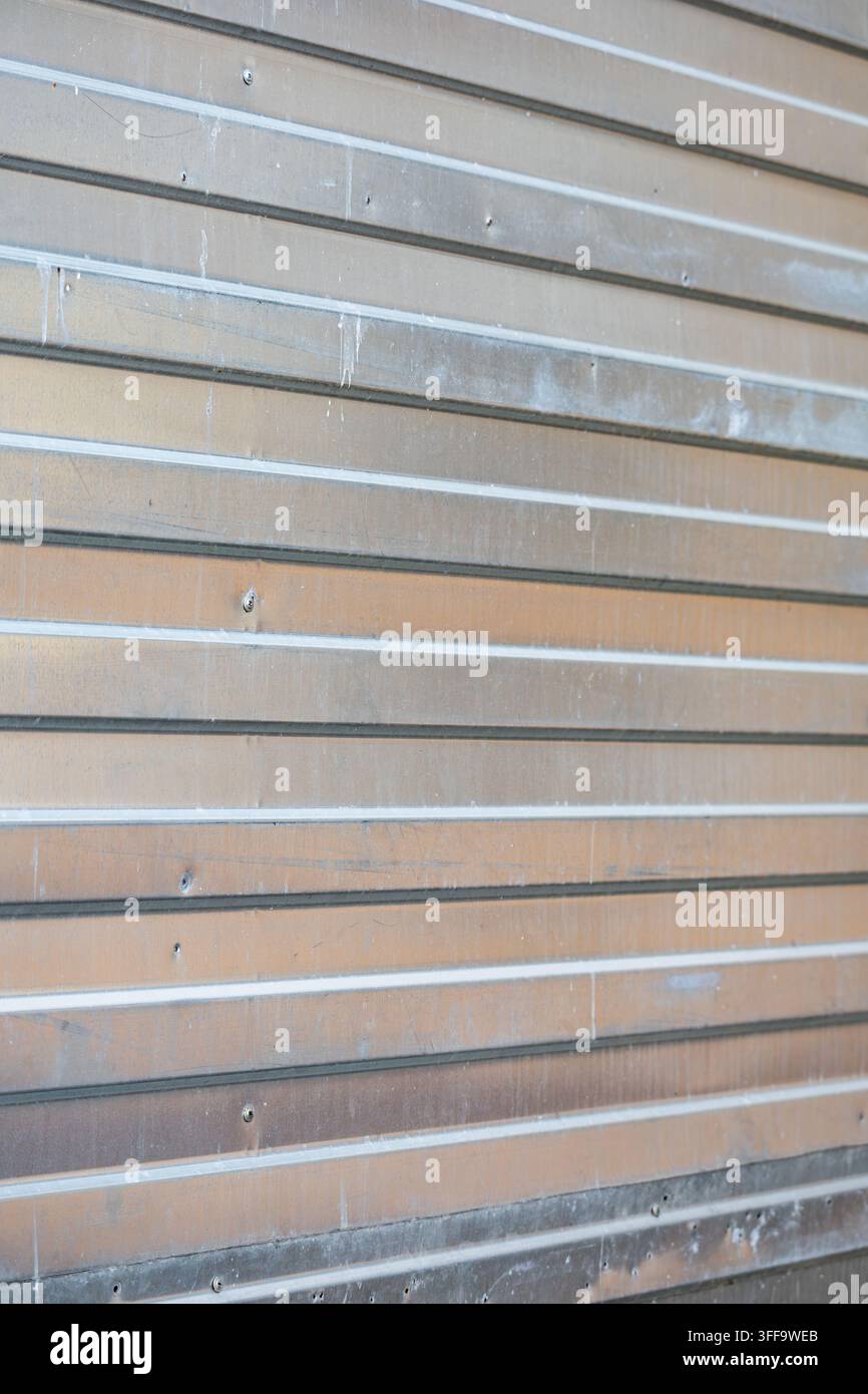 Abstrakte Perspektivansicht einer sauberen gerippten Stahlwandverkleidung mit linearen silbernen horizontalen Linien und natürlichen Lichtreflexionen. Stockfoto