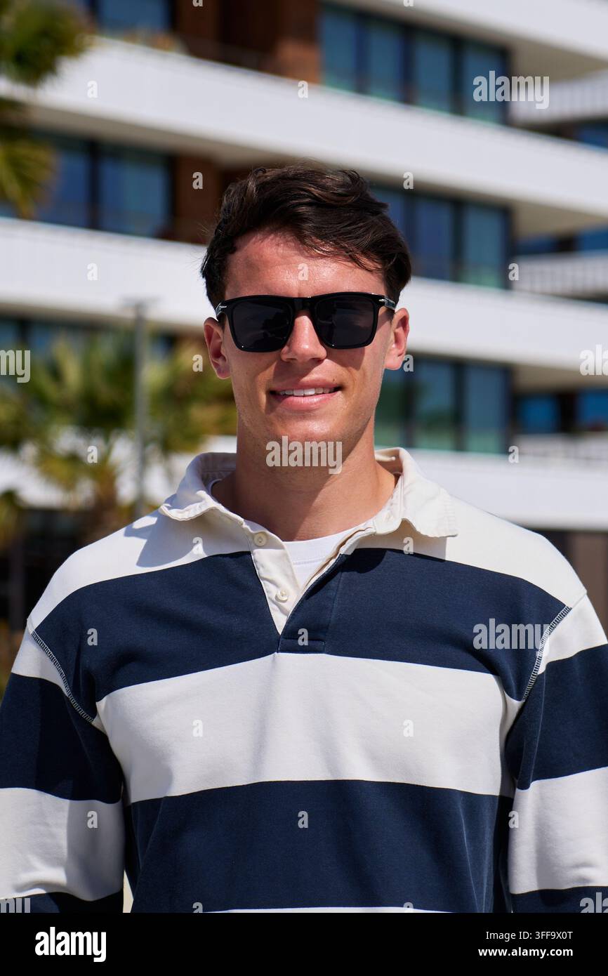 Junger Mann mit Sonnenbrille in der Yachthafenanlage Stockfoto