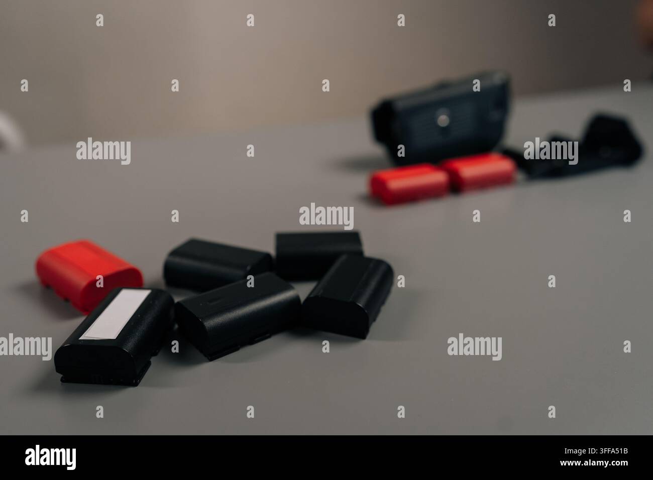 Digitales Kamerasystem mit Stromversorgungszubehör und mehreren geladenen, entladenen roten und schwarzen Lithium-Ionen-Akkus für den professionellen Einsatz Stockfoto