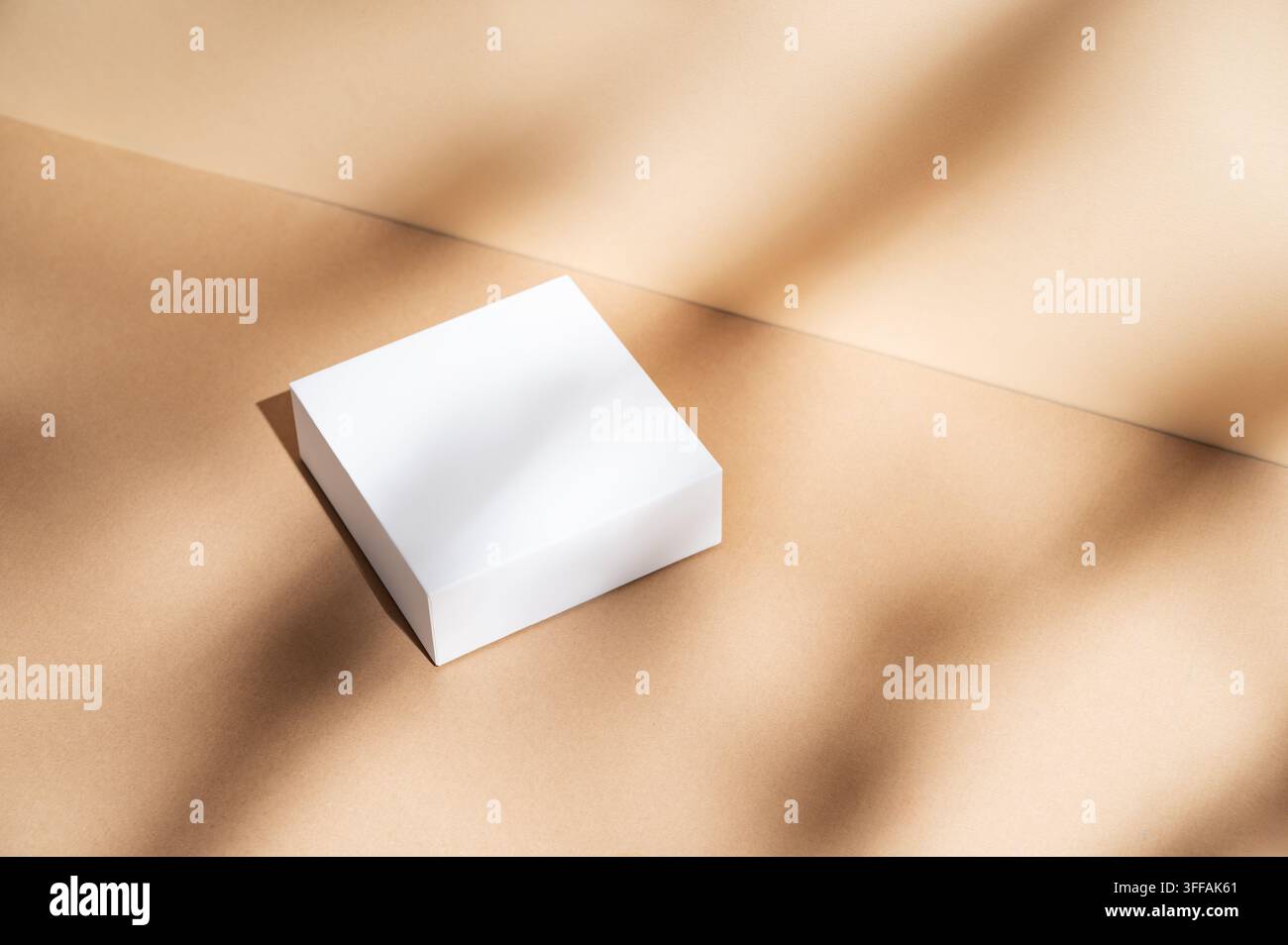 Weiße quadratische Kisten auf einem beigen Hintergrund mit natürlichem Licht und Schatten. Konzept abstraktes geometrisches Design für Werbung oder Produktpräsentation. T Stockfoto