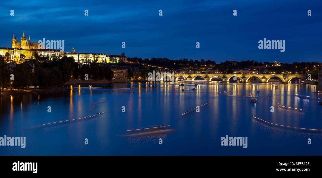Boote bewegen sich auf dem Fluss, während Lichter sich auf dem Wasser in Prag nach Sonnenuntergang spiegeln. Stockfoto