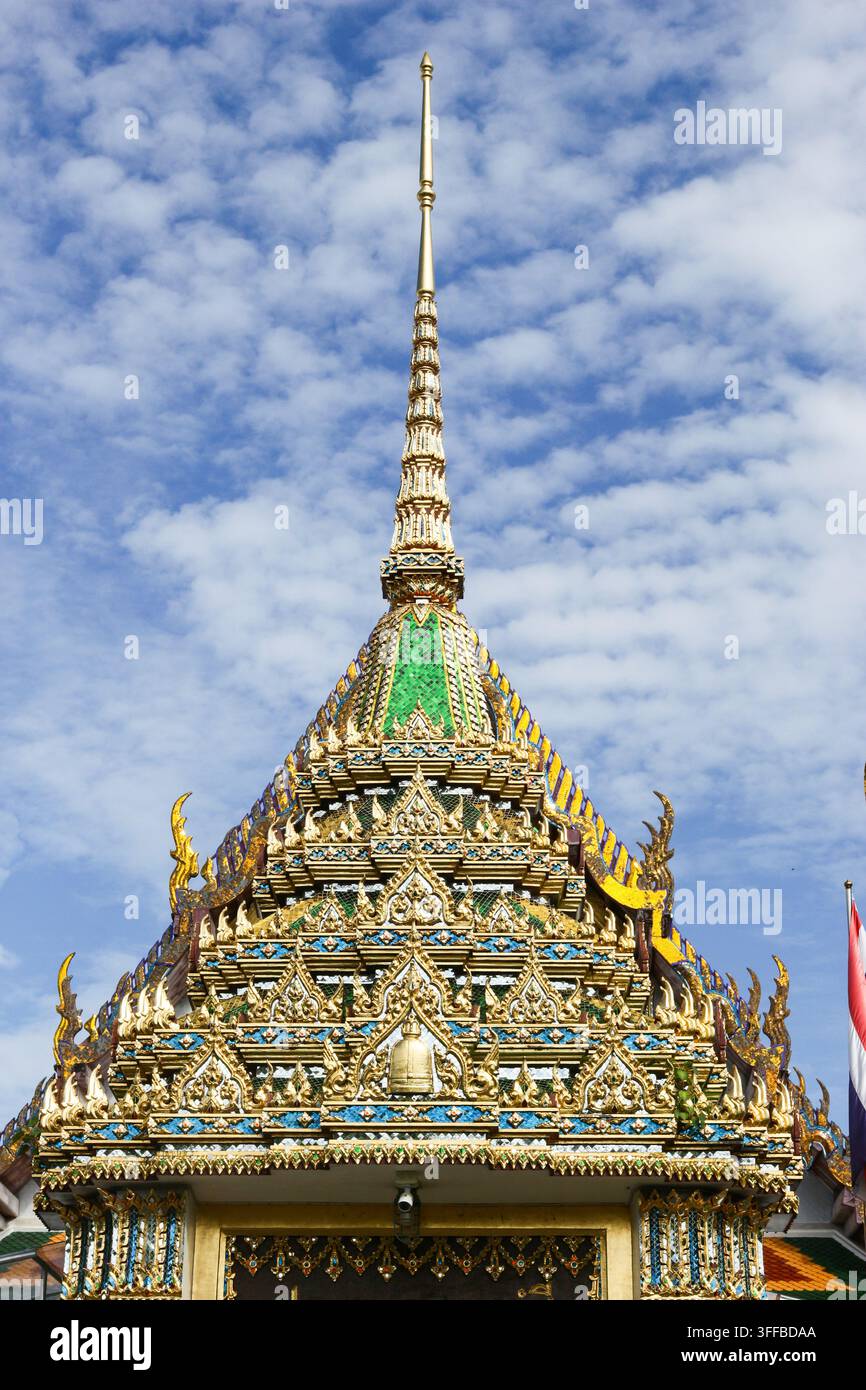 Verschnörkelter goldener Turm und gestuftes Dach des Tempeltors von Wat Rakhang Khositaram, Bangkok, Thailand, aus einem niedrigen Winkel gesehen. Stockfoto