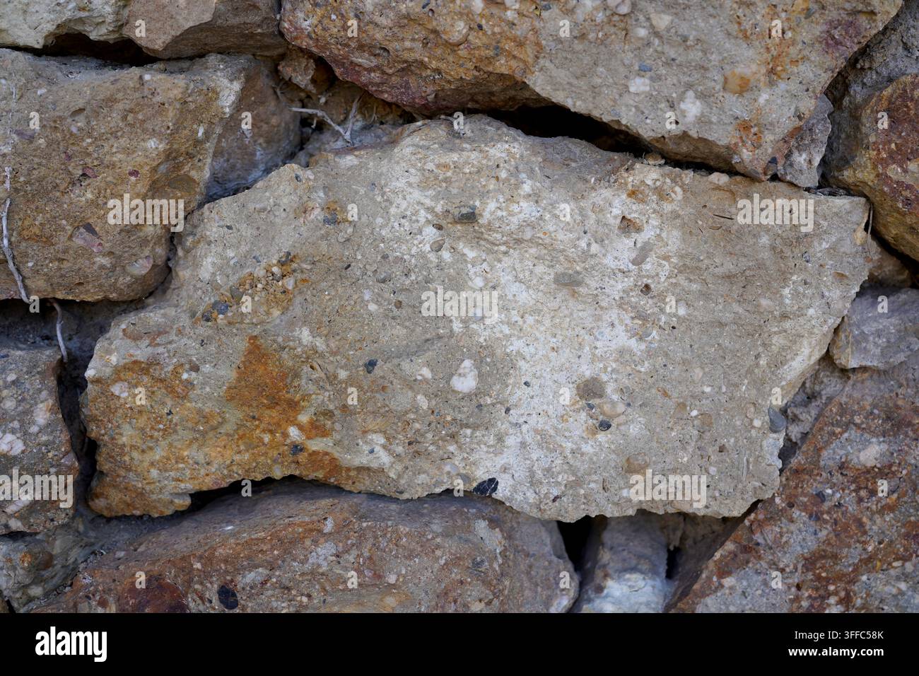 Detaillierte Nahaufnahme einer verwitterten Steinmauer, die raue Texturen und natürliche Steinfarben in Barcelona, Spanien, zeigt Stockfoto