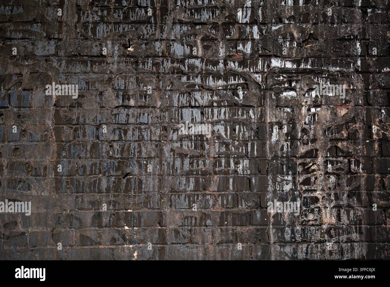 Angebrannte Ziegelwand mit schwarzer Rußtextur im Hintergrund. Stockfoto