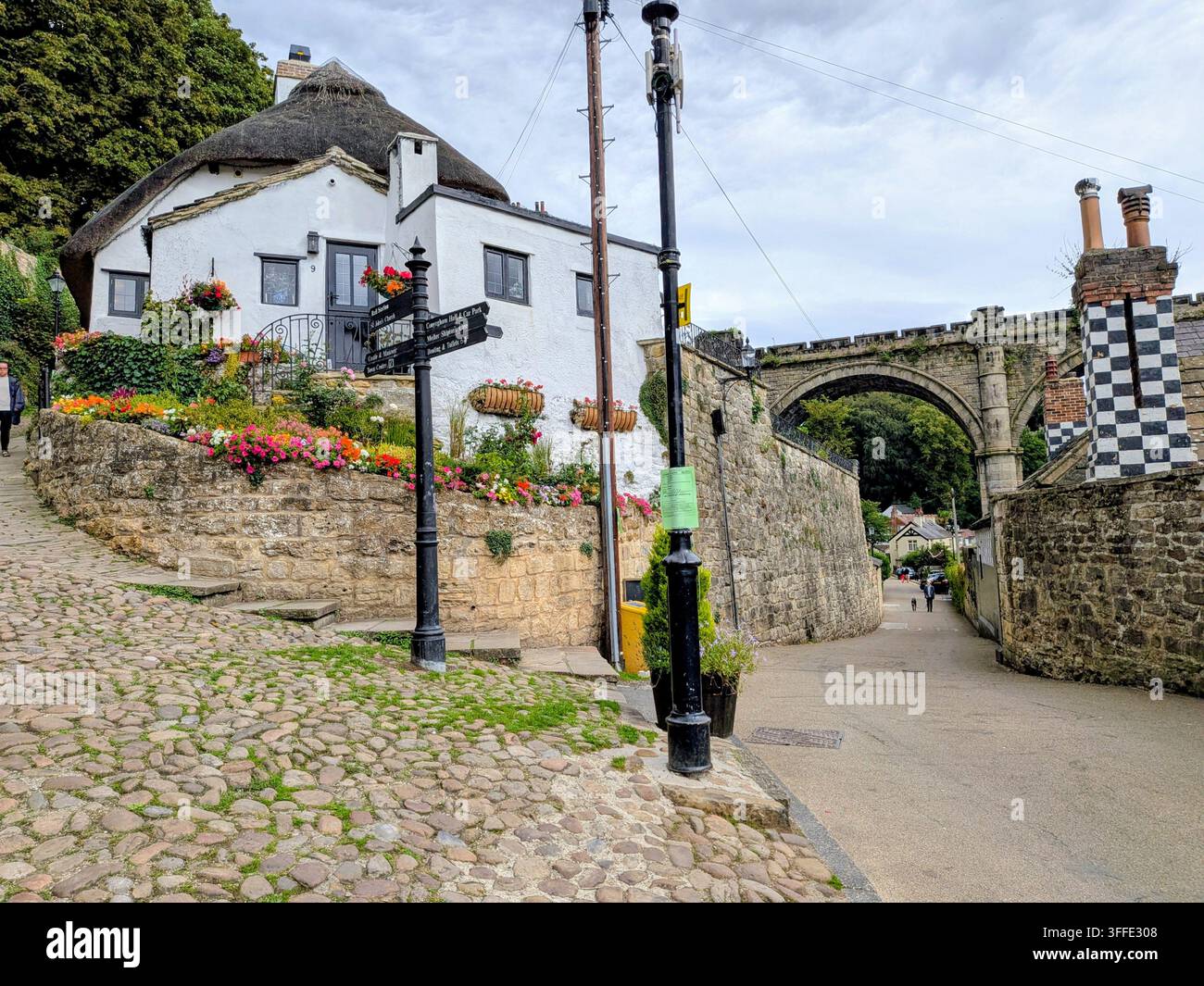 Weiße Stunde mit Strohdach und steinerner Bogenbrücke in KNaresborough Stockfoto