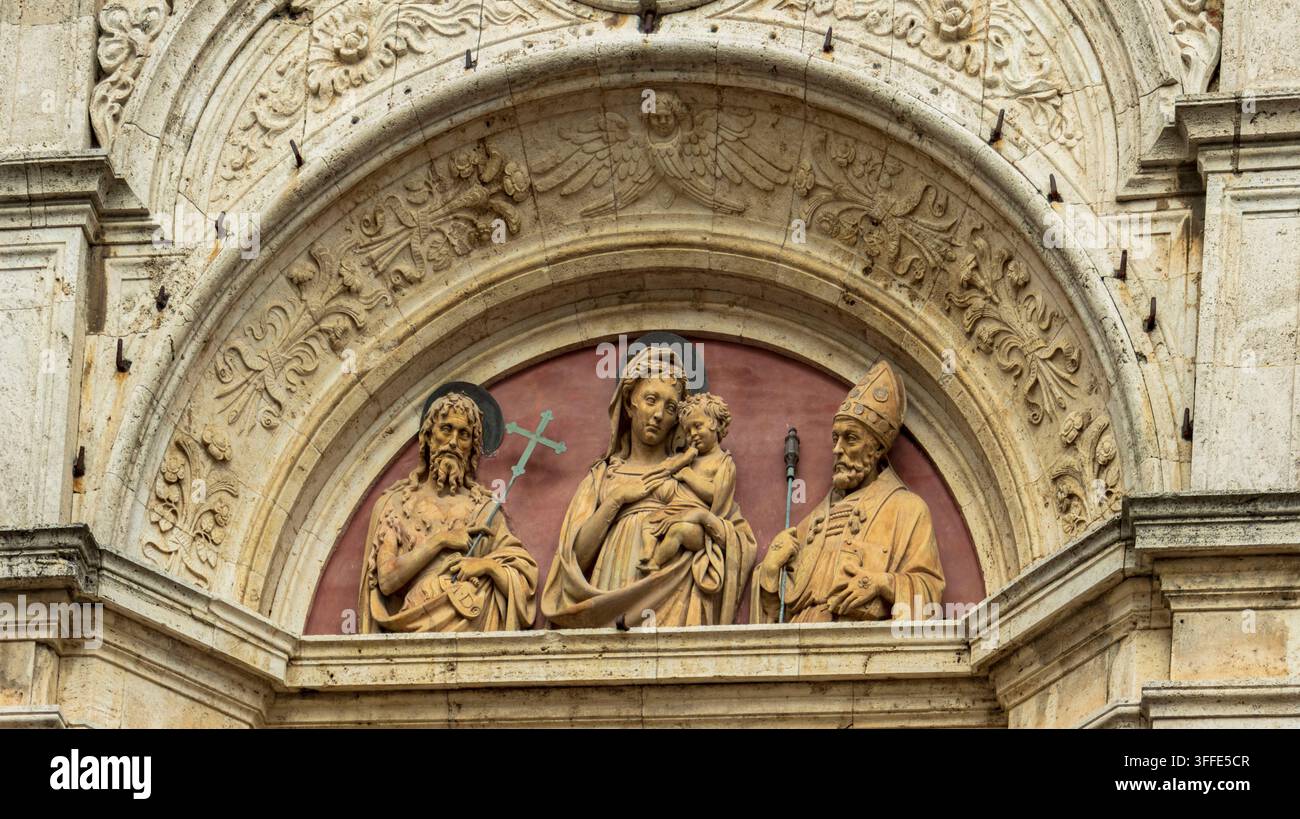 Bildhauerisches Relief der Jungfrau Maria mit Jesus und Heiligen über dem Portal der Kathedrale von Pienza. Stockfoto