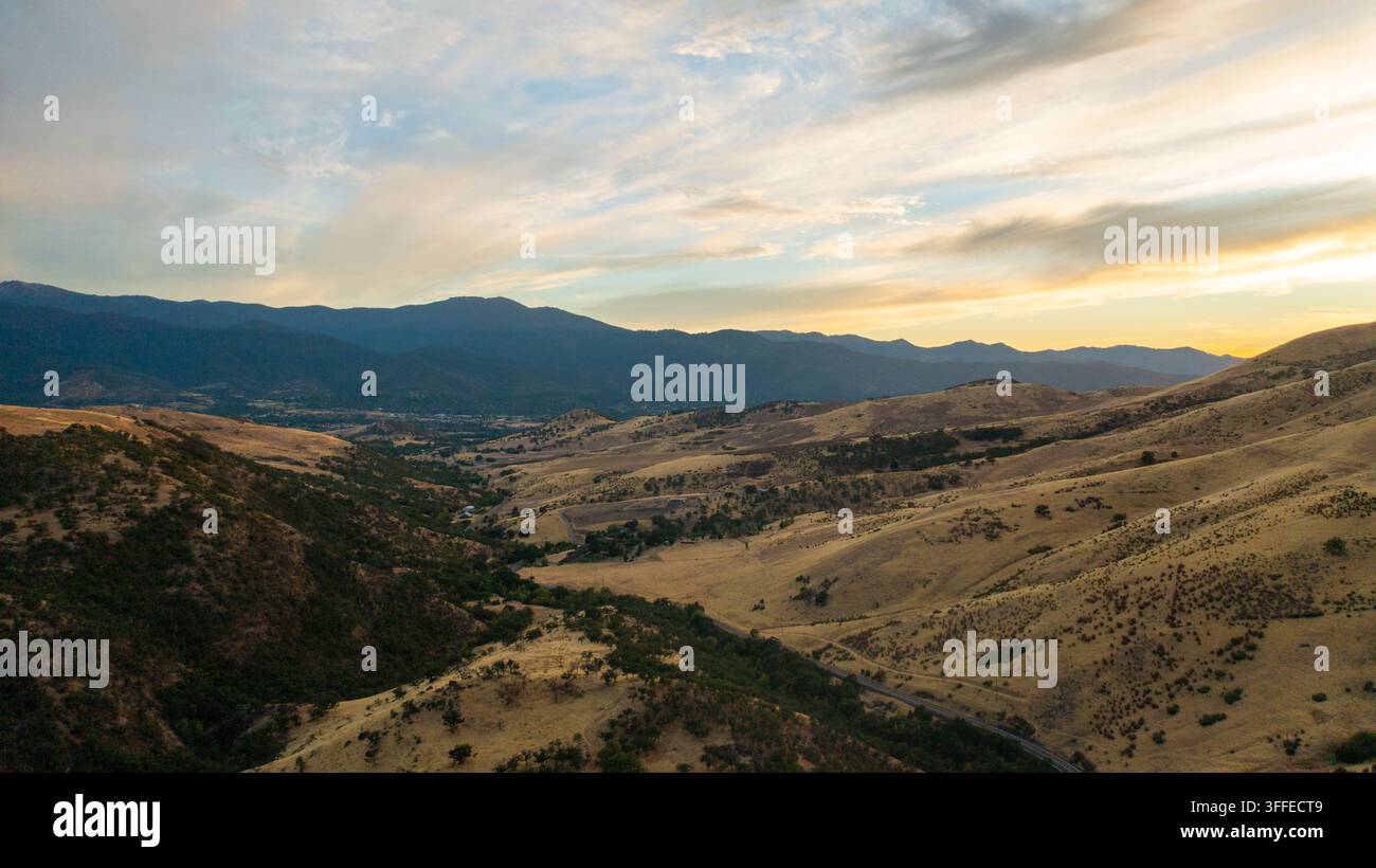 Luftaufnahme des Cascade-Siskiyou-Nationalmonuments mit sanften goldenen Hügeln, trockenen grasbewachsenen Hängen und fernen Bergketten unter einem sanften Sonnenuntergang s Stockfoto