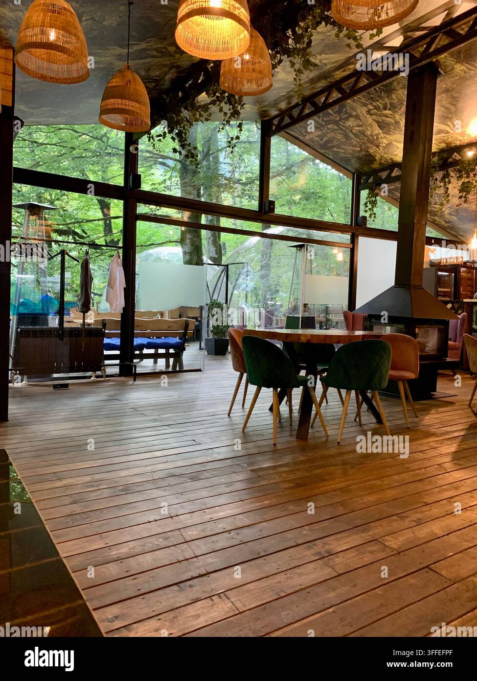 Ein leeres Waldrestaurant kombiniert Glaswände, Holzböden und warme Beleuchtung. - Smartphone-aufgenommenes Stockfoto