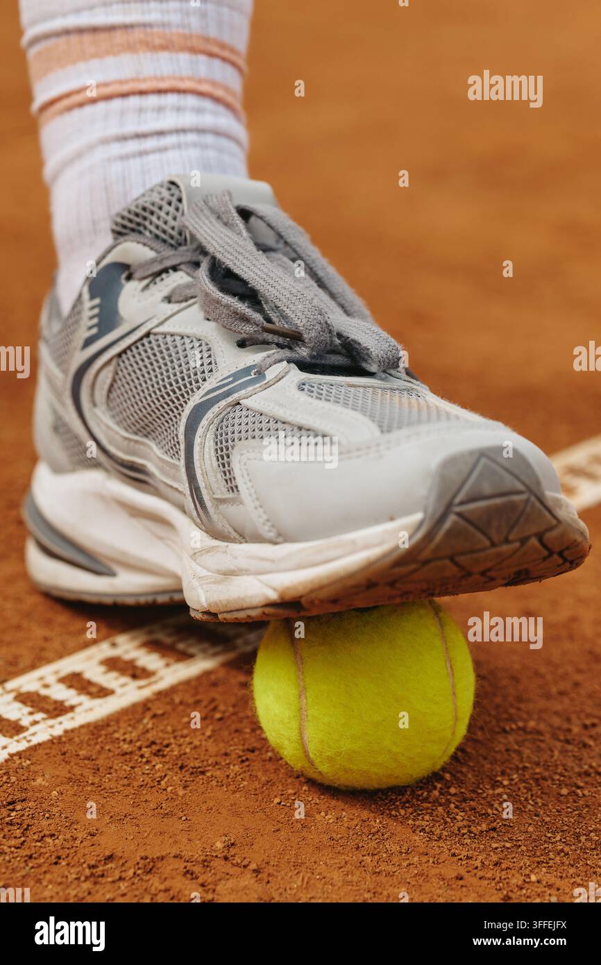 Tennisspieler-Fuß tritt auf einen Tennisball auf Sandplatz Stockfoto