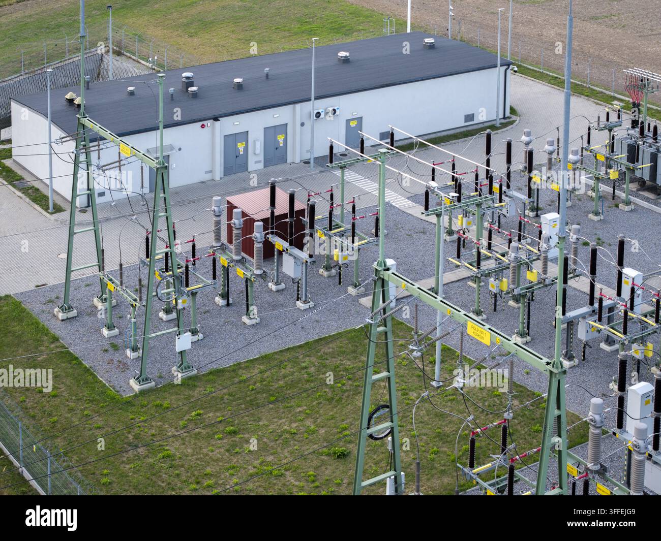 Luftbild einer 11015-kV-Transformatorenstation mit elektrischen Geräten, Metallmasten und einem kleinen Versorgungsgebäude in einem eingezäunten Industriegebiet in Polen. Stockfoto