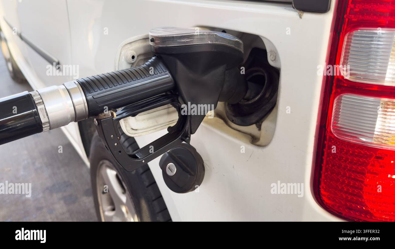 Nahaufnahme eines Kraftstoffschlauchs, der ein Auto an einer Tankstelle betankt, veranschaulicht Kraftstoffpreise, steigende Transportkosten, Inflation, Energiekosten und Haus - Smartphone-aufgenommenes Stockfoto