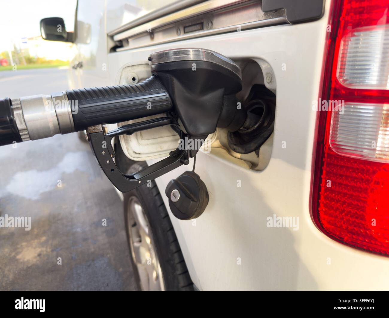 Nahaufnahme eines Kraftstoffschlauchs, der ein Auto an einer Tankstelle betankt, veranschaulicht Kraftstoffpreise, steigende Transportkosten, Inflation, Energiekosten und Haus - Smartphone-aufgenommenes Stockfoto