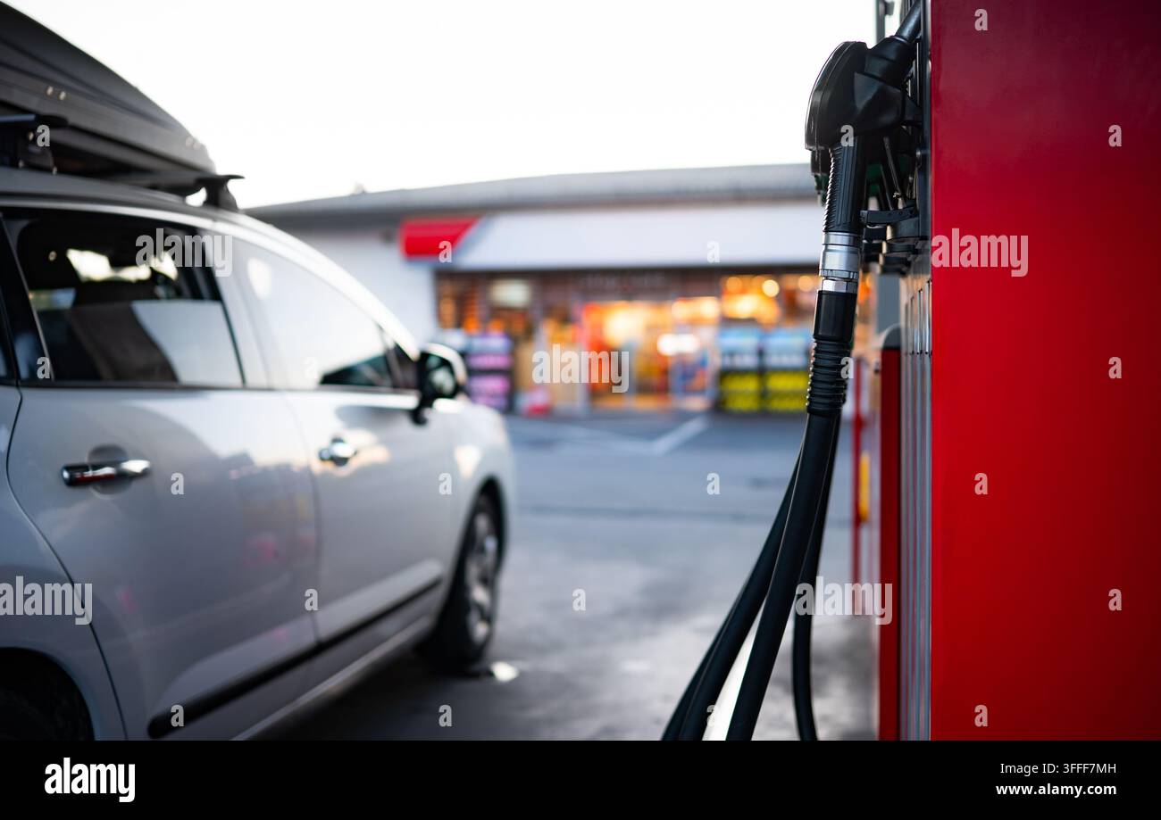Weißes Auto mit Dachträger, gefüllt mit Benzin an der Tankstelle, bereit für eine lange Reise Stockfoto