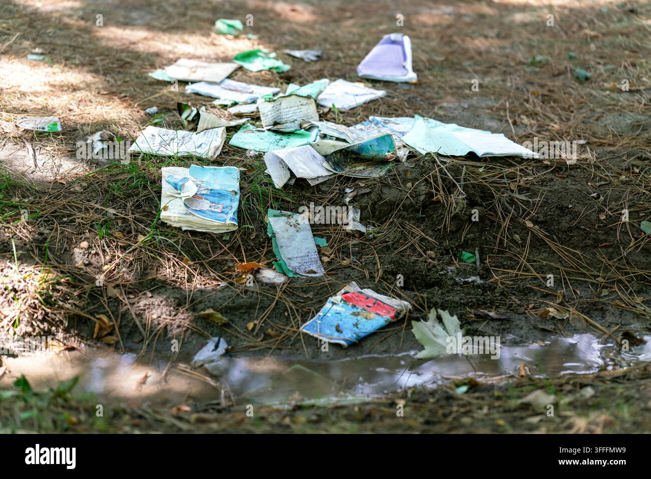 Verstreute und zerrissene Grundschulhefte, die in einem abgelegenen Parkbereich zurückgelassen wurden, repräsentieren den überwältigenden Druck von Studien und Prüfungsangst. Stockfoto