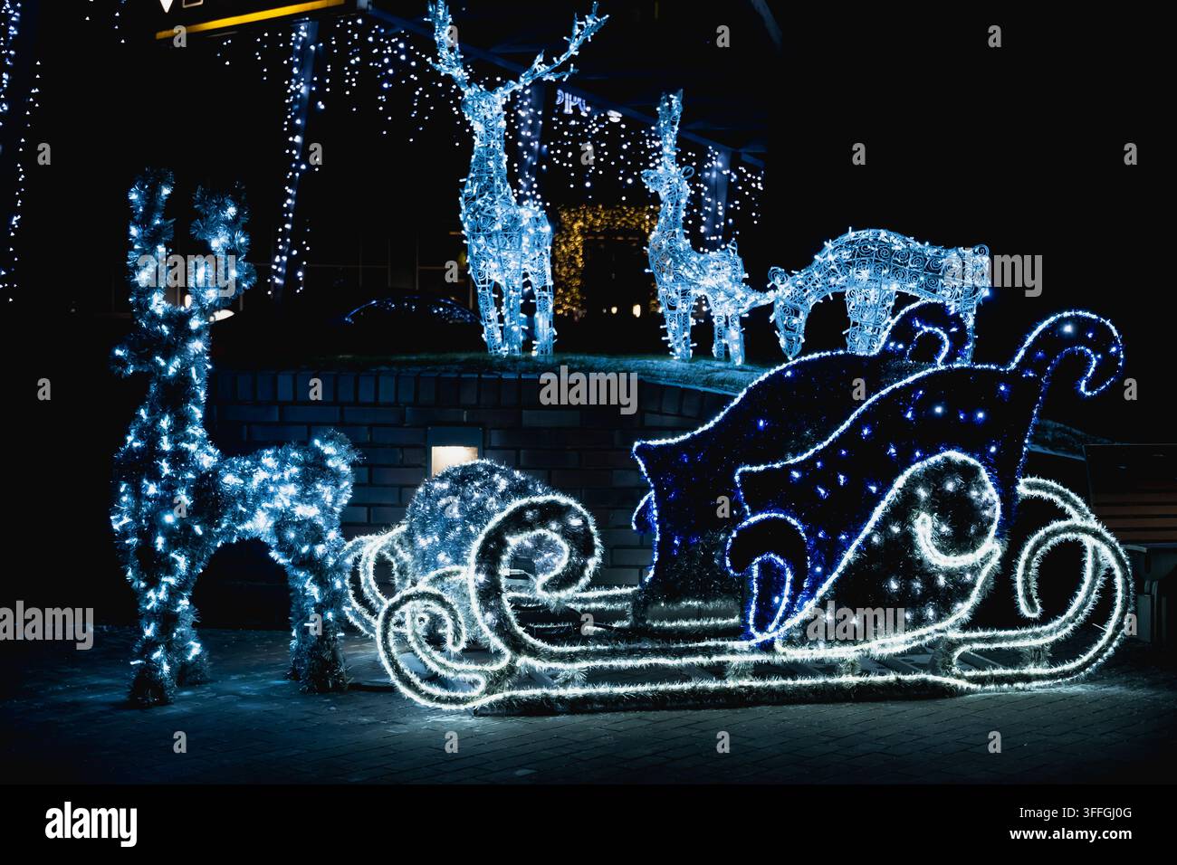 Leuchtende Weihnachtsmannschlitten- und Rentier-Lichtskulpturen in der Weihnachtsdekoration im Freien bei Nacht, festliche Winterbeleuchtung und Feiertagspräsentation. Stockfoto