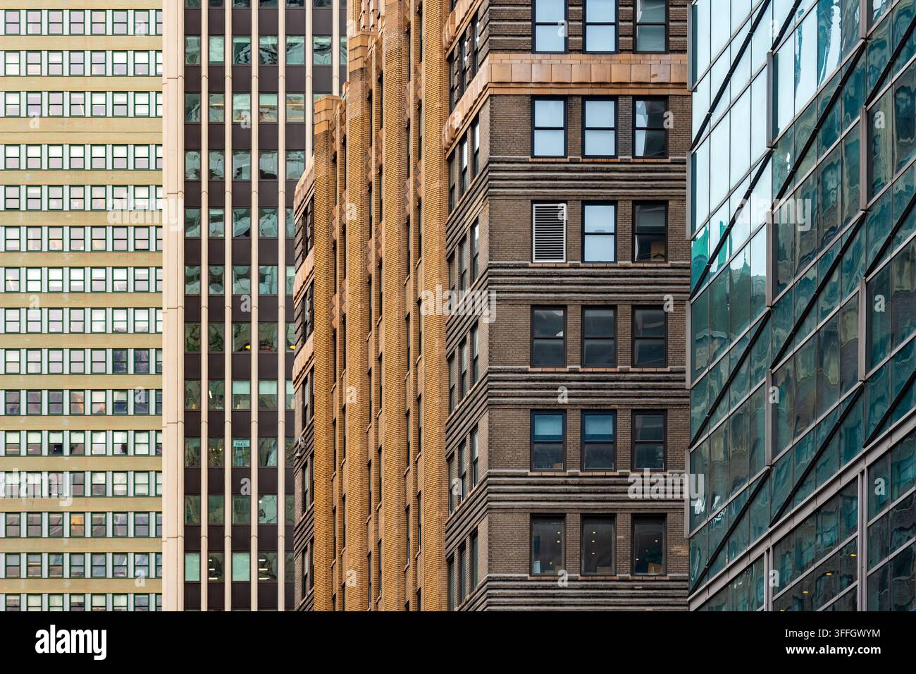 Geometrische Texturen und architektonische Muster von historischen Backstein- und modernen Glasgebäuden schaffen ein geschichtetes visuelles Design über die Fassaden von Wolkenkratzern. Stockfoto