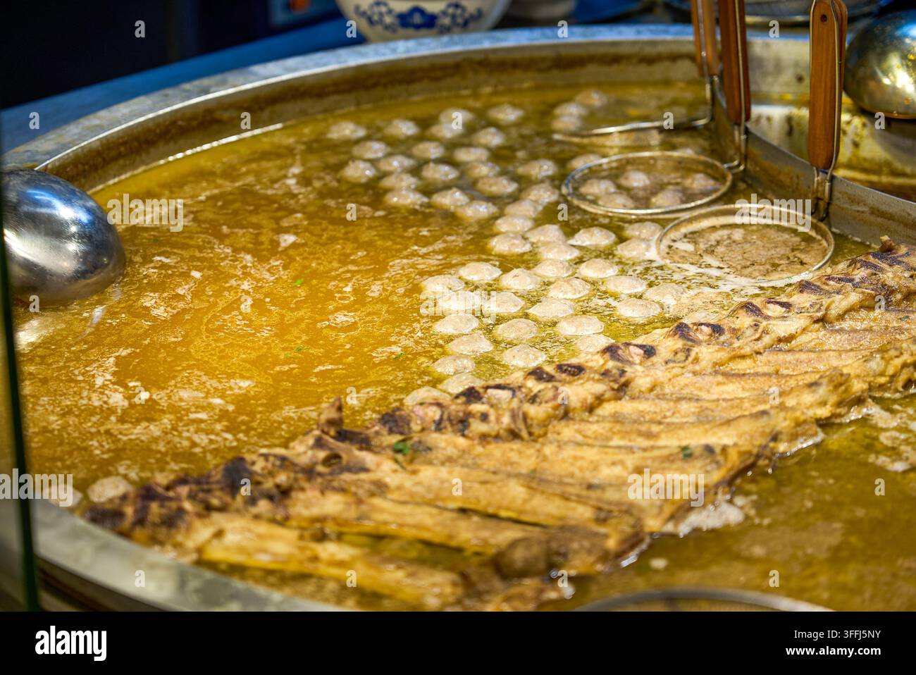 Im großen Topf am Guizhou-Rindfleisch-Nudelnstand kocht eine goldene Rindfleischsuppe und Rindfleischbällchen köcheln langsam. Stockfoto