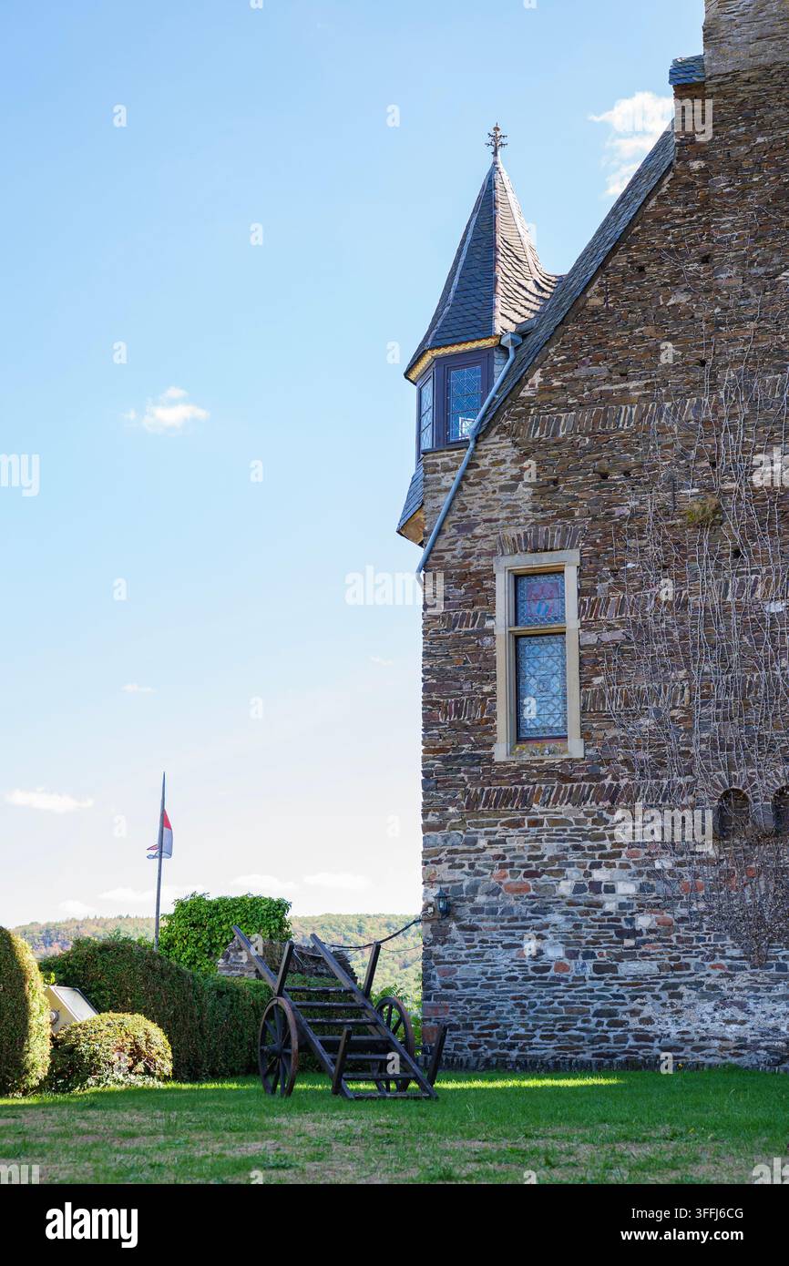 Burg mittelalterliche historische Architektur Steingebäude mit Turm, alter Holzwagen auf Rasen und Fahne unter blauem Himmel Stockfoto