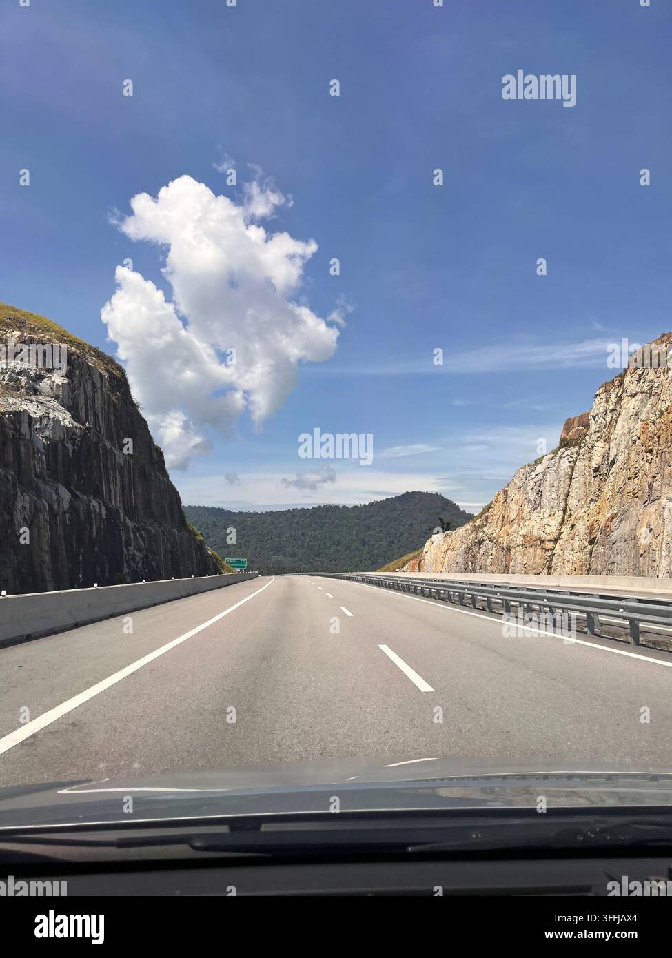 Scenische Bergstraße zwischen felsigen Klippen unter blauem Himmel. - Smartphone-aufgenommenes Stockfoto