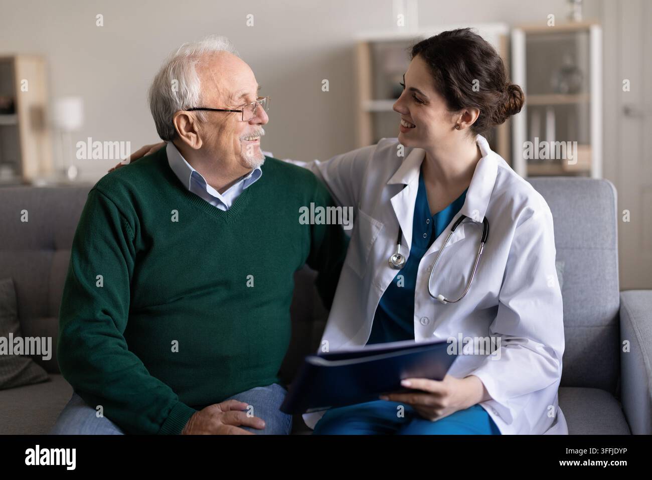 Seniorer Mann, der sich mit einer Ärztin bei einem Hausbesuch berät Stockfoto
