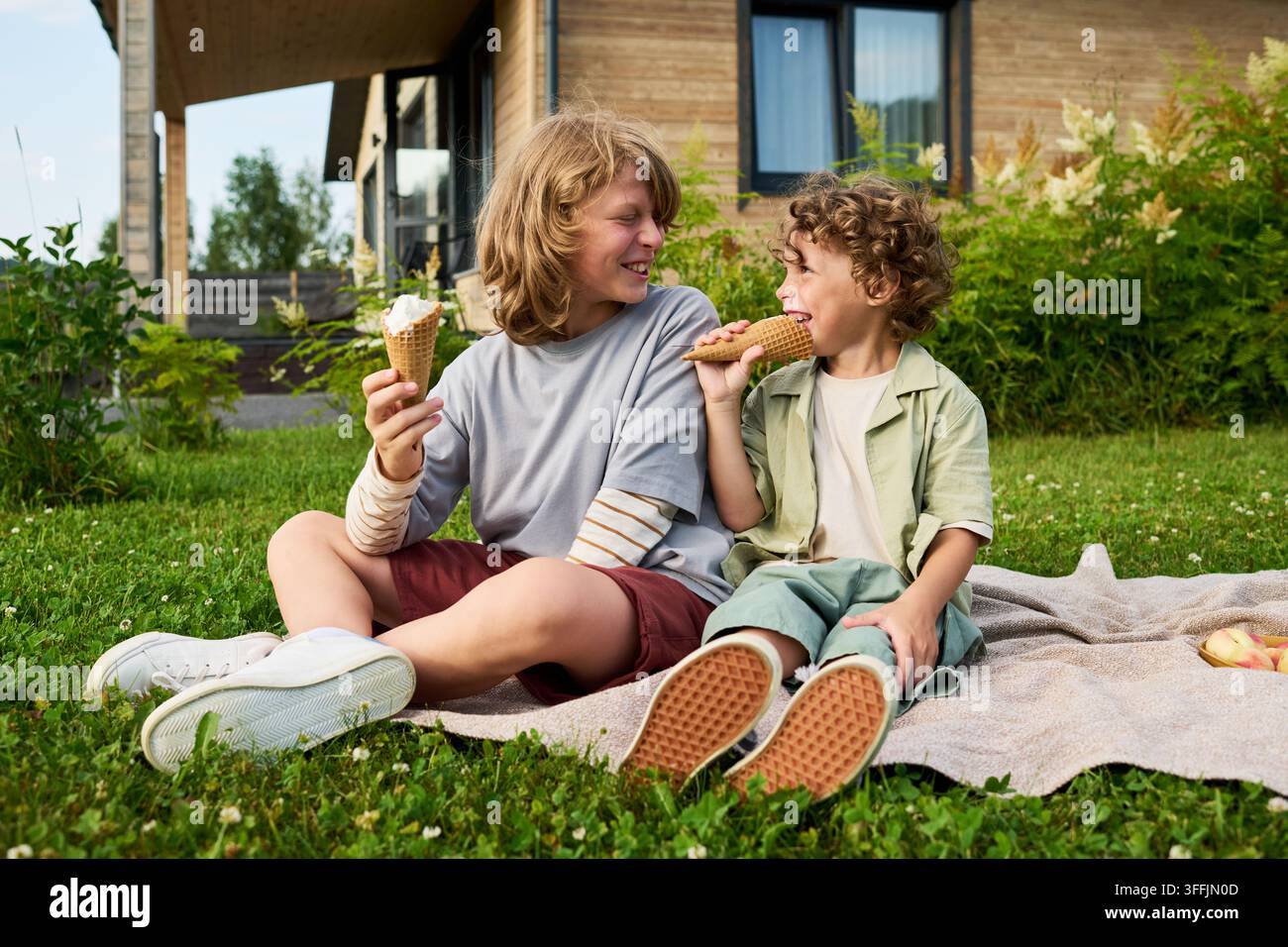 Zwei Brüder essen Eiscremekuchen während eines Picknicks im Hinterhof Stockfoto