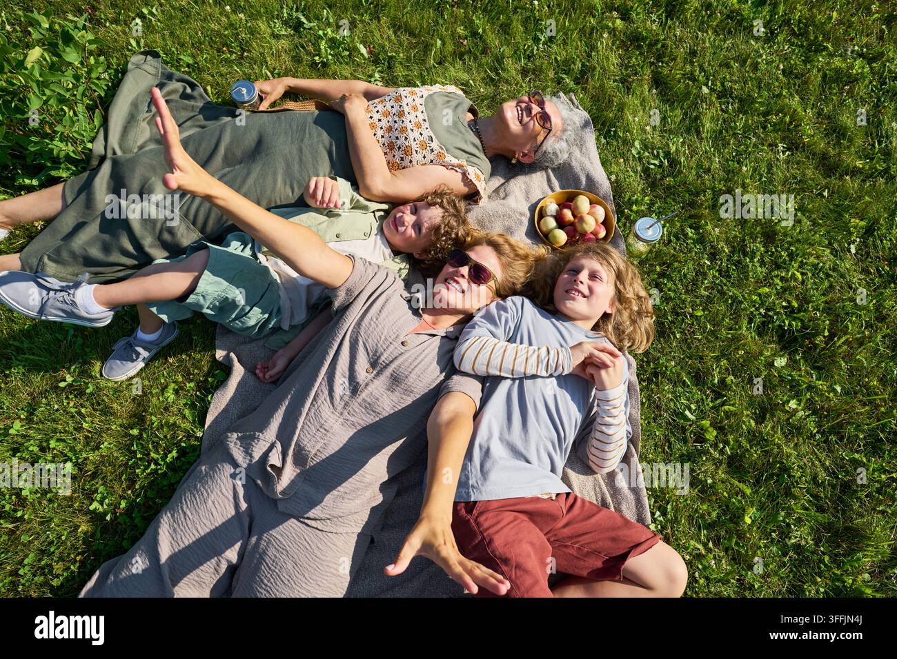 Fröhliche multigenerationale Familie entspannt sich auf dem Gras während eines Picknicks Stockfoto