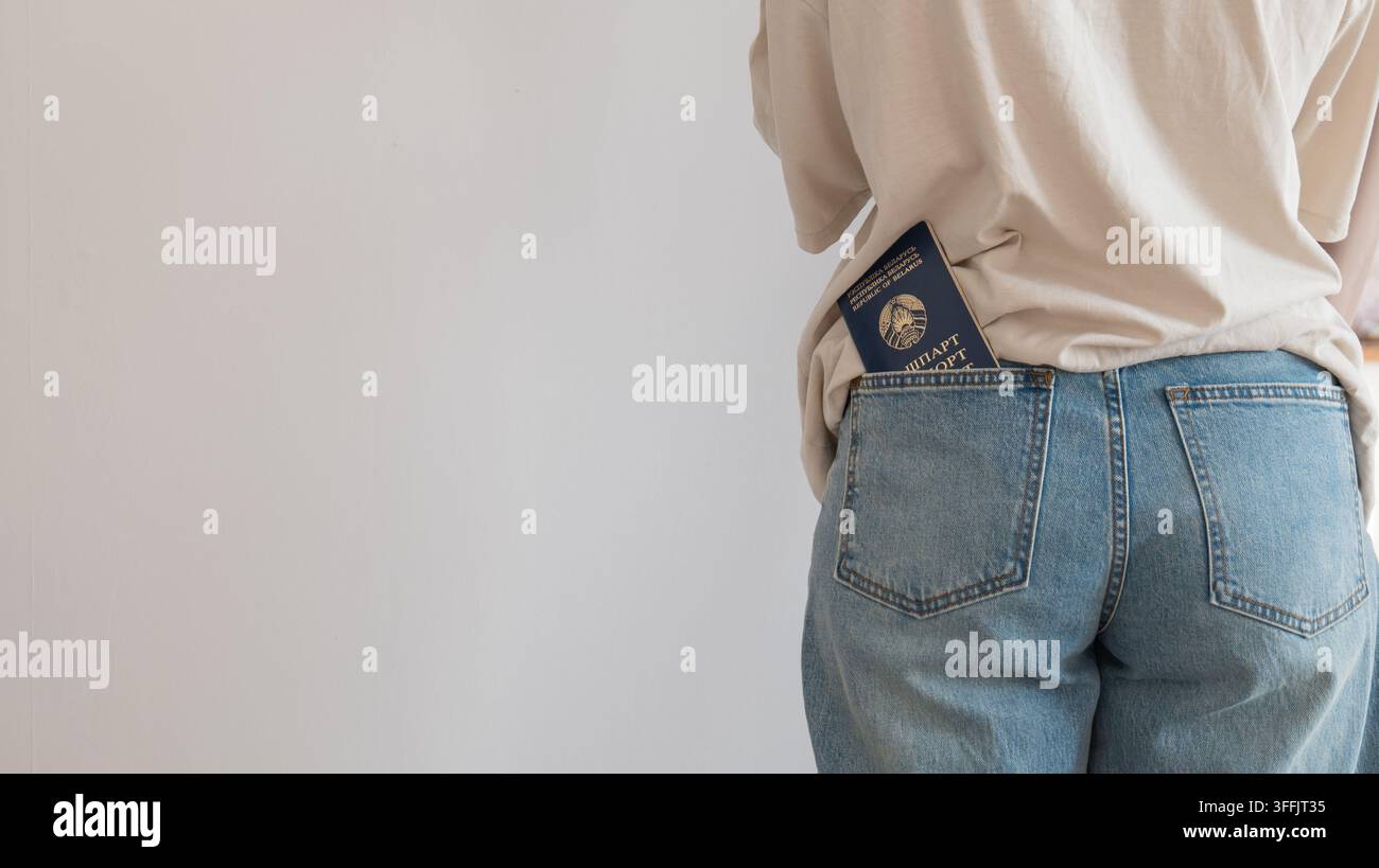 Eine Person, die Jeans und ein T-Shirt trägt, steht still in einer Innenumgebung mit einer neutralen Stimmung, umgeben von hellblauen und beigen Farben. Dieses Bild ist t Stockfoto
