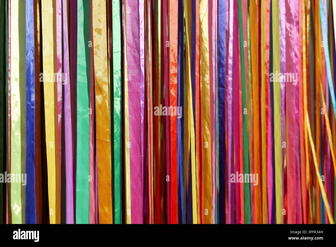 bunte Bänder, die drinnen hängen, hell und festlich, Nahaufnahme mit Stoffmaterialien und lebhaften Farben in einer natürlichen Lichtumgebung für Stockfoto
