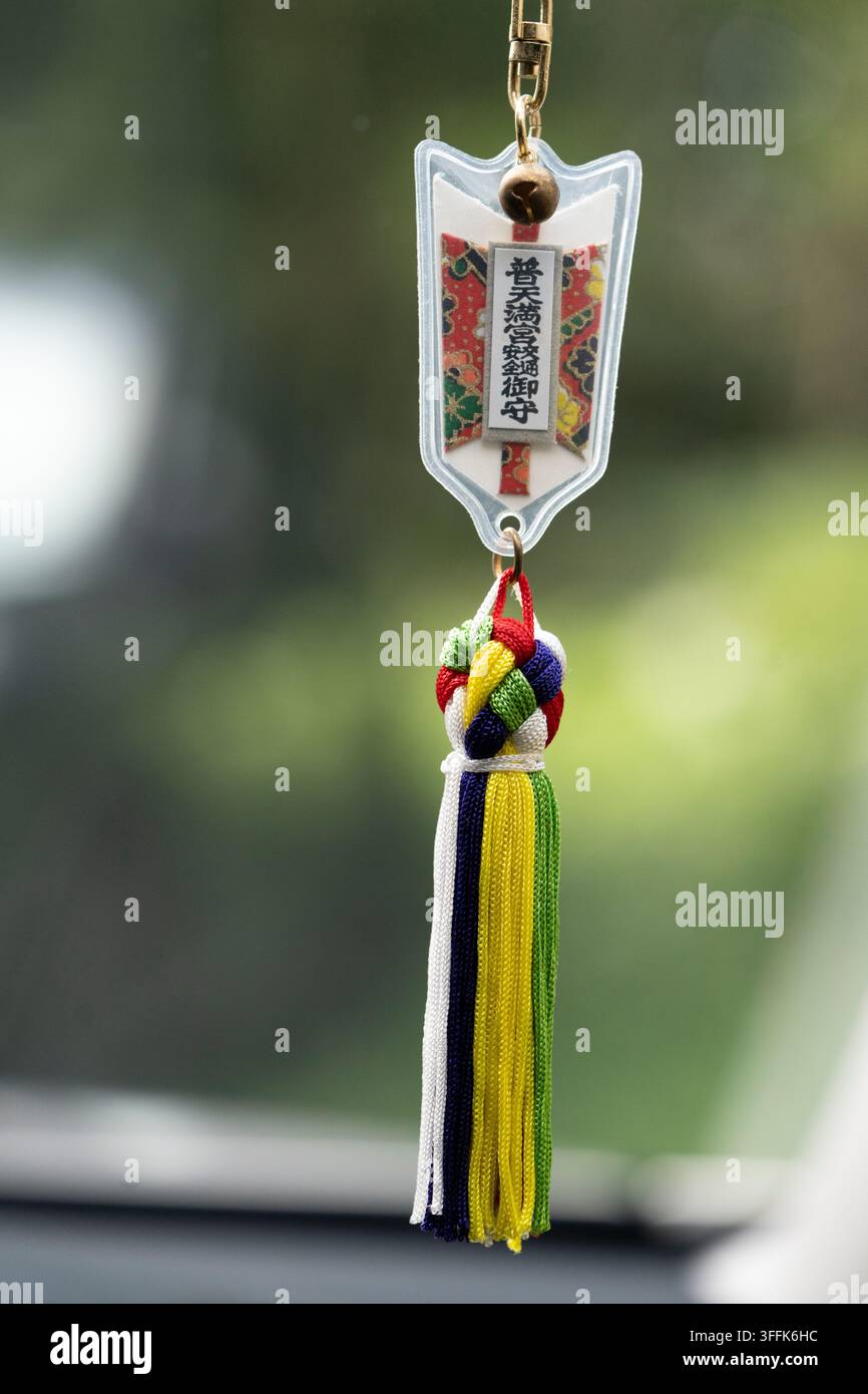 Ein japanisches Schutzamulett für sicheres Fahren (Omamori), das an einem Autofenster im Innenraum hängt. Stockfoto