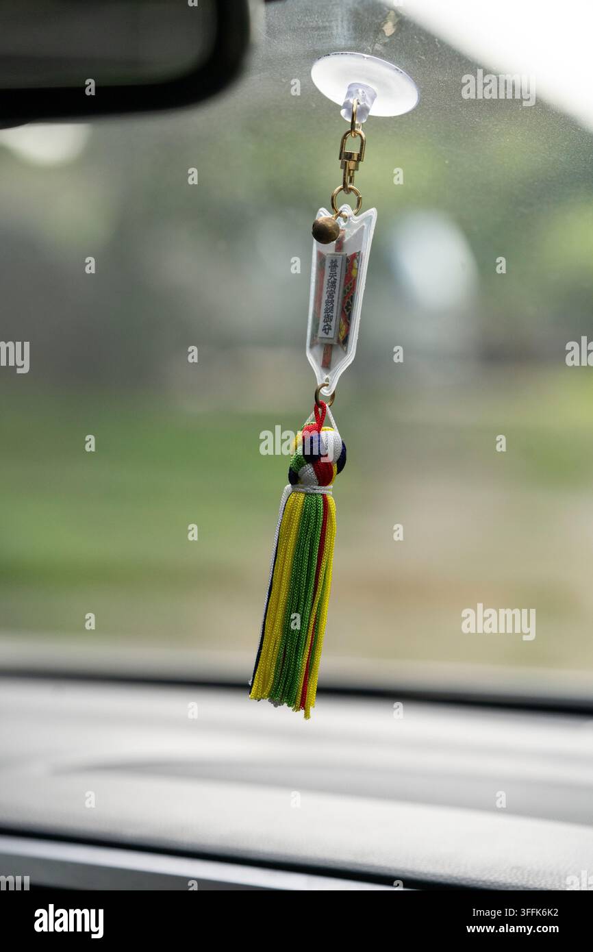 Ein japanisches Schutzamulett für sicheres Fahren (Omamori), das an einem Autofenster im Innenraum hängt. Stockfoto