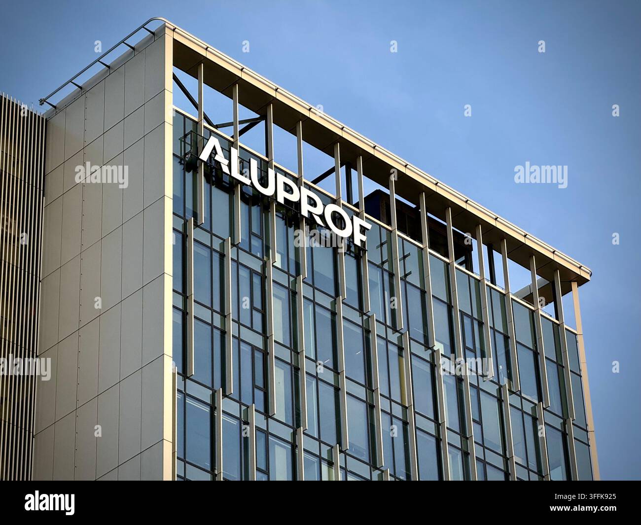 Niedrigwinkelaufnahme des Aluprof-Firmenzeichens an einer modernen Glasfassade mit Metallpaneelen in Vilnius, Litauen. - Smartphone-aufgenommenes Stockfoto