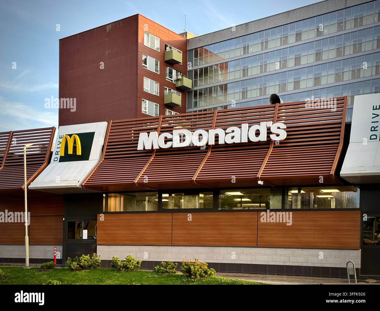 Niedrigwinkelfoto eines McDonald's-Restaurants und einer McDrive-Einrichtung vor einem mehrstöckigen Wohngebäude in Vilnius, Litauen. - Smartphone-aufgenommenes Stockfoto