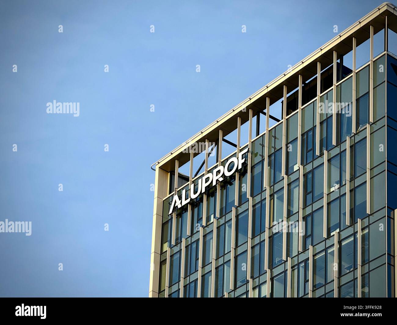 Niedrigwinkelaufnahme des Aluprof-Firmenzeichens an einer modernen Glasfassade mit Metallpaneelen in Vilnius, Litauen. - Smartphone-aufgenommenes Stockfoto