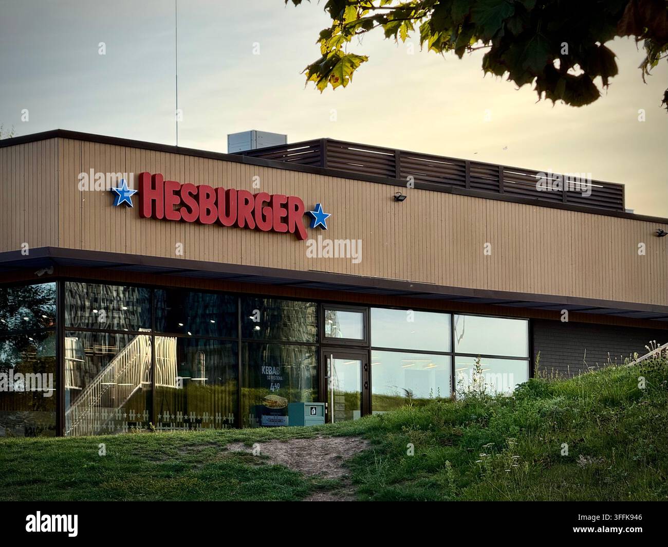 Niedrigwinkelaufnahme eines modernen Hesburger-Fastfood-Restaurants mit Holzfassade und Glasfront in Vilnius, Litauen. - Smartphone-aufgenommenes Stockfoto