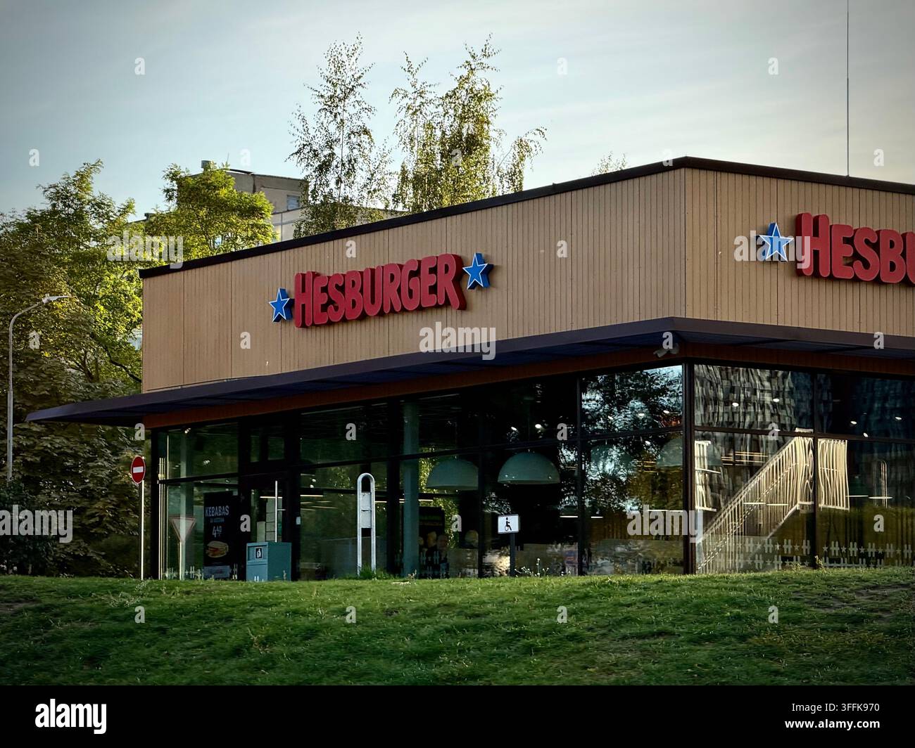 Augenhöhe-Foto eines modernen Hesburger-Fastfood-Restaurantpavillons mit Holzfassadenplatten und Glasvitrinen in Vilnius, Litauen. - Smartphone-aufgenommenes Stockfoto