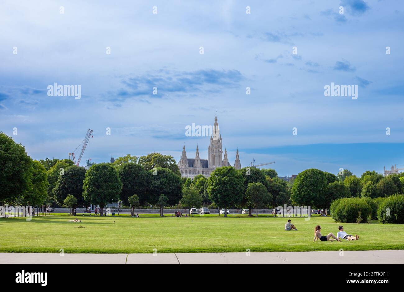 Gartenpark Wiener Rathaus vom Volksgarten aus mit entspannenden Menschen unter blauem Sommerhimmel. Wien, Österreich - 21. Juni 2026 Stockfoto