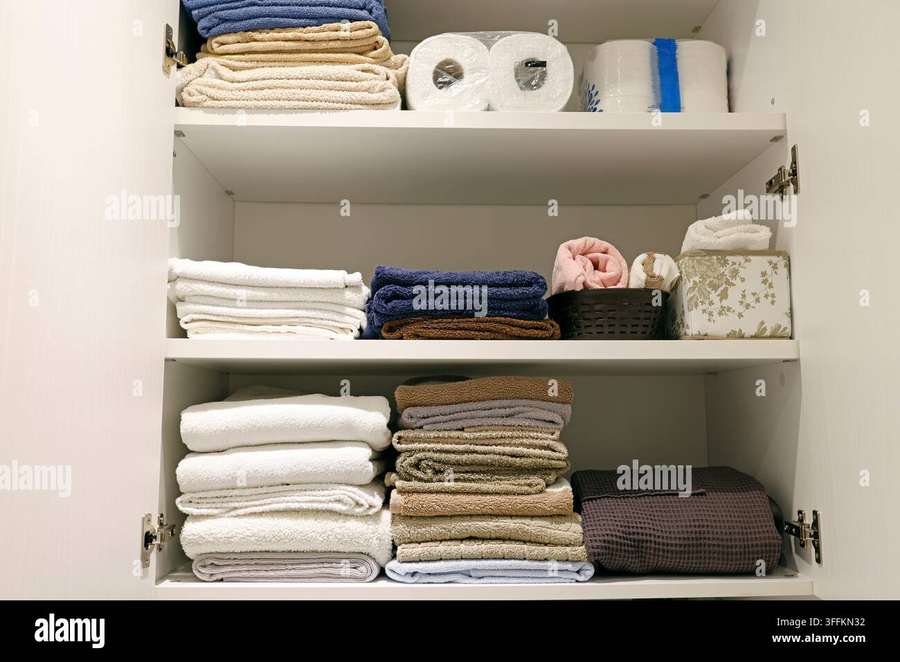 Organisierte Badezimmerschranksregale mit gestapeltem gefaltetem Leinen. Stockfoto