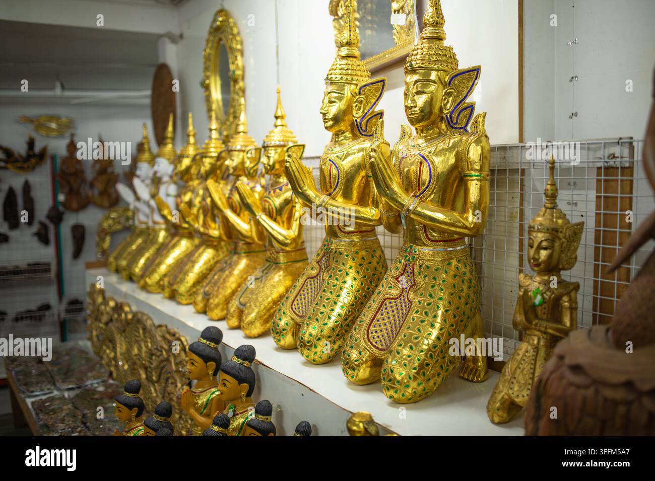Große goldene Thepphanom-Statuen stehen zusammengelegt mit Handflächen in der Wai-Gebetshaltung, traditionelle thailändische Wächterfiguren zeigen kunstvolle Handwerkskunst Stockfoto