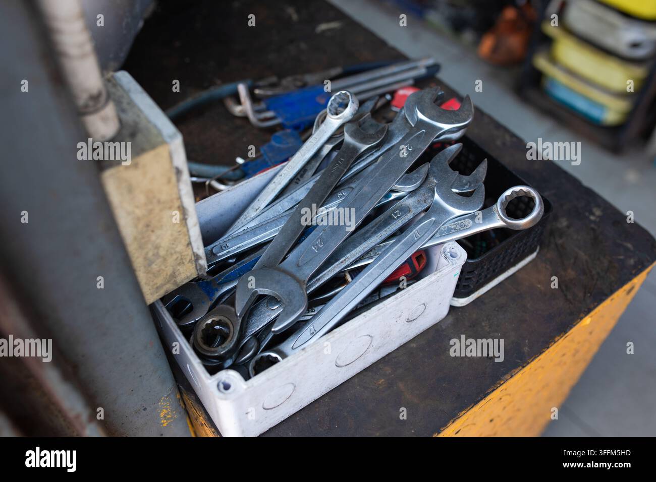 Verschiedene Schraubenschlüssel füllen eine offene Werkzeugschublade in einer geschäftigen Werkstatt, abgenutzte Metallwerkzeuge zeigen häufigen Gebrauch, bereit für Reparaturaufgaben am Arbeitsplatz der Autowerkstatt Stockfoto