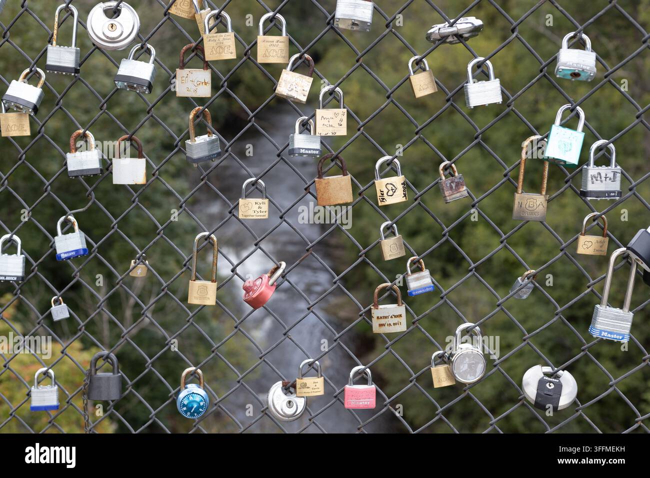 Schlösser, die an einem Maschendrahtzaun auf einer Fußgängerbrücke über den Vermillion River in Hastings, Minnesota, befestigt sind. Stockfoto