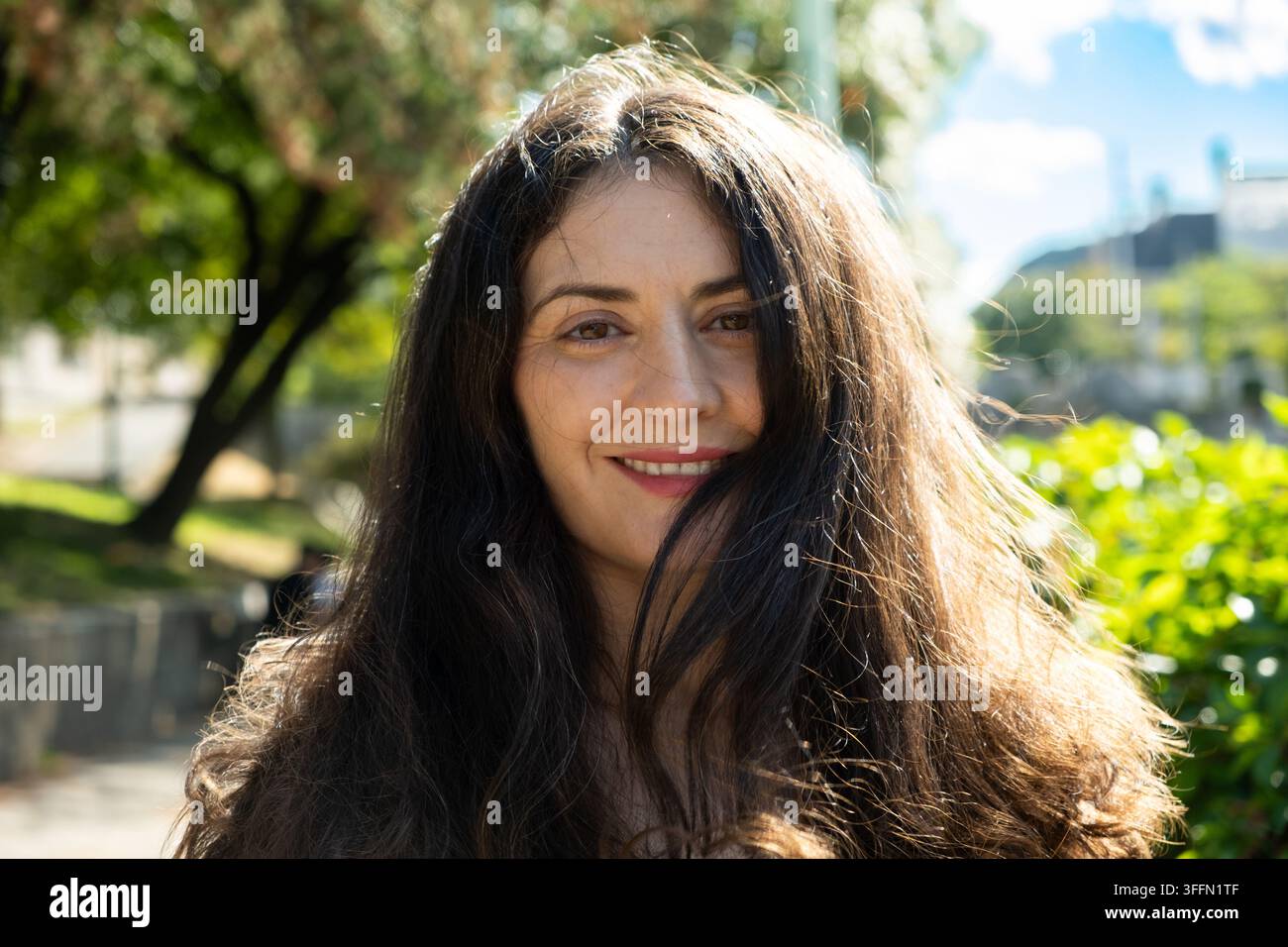 Schöne Frau mit dichtem langem dunklem Haar, das von warmem natürlichem Sonnenlicht angestrahlt wird. Stockfoto
