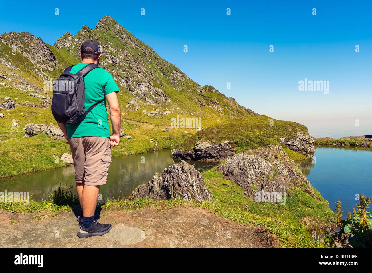 Wanderer mit Rucksack neben einem kleinen Bergsee in den Karpaten in der Transsilvania, Rumänien Stockfoto
