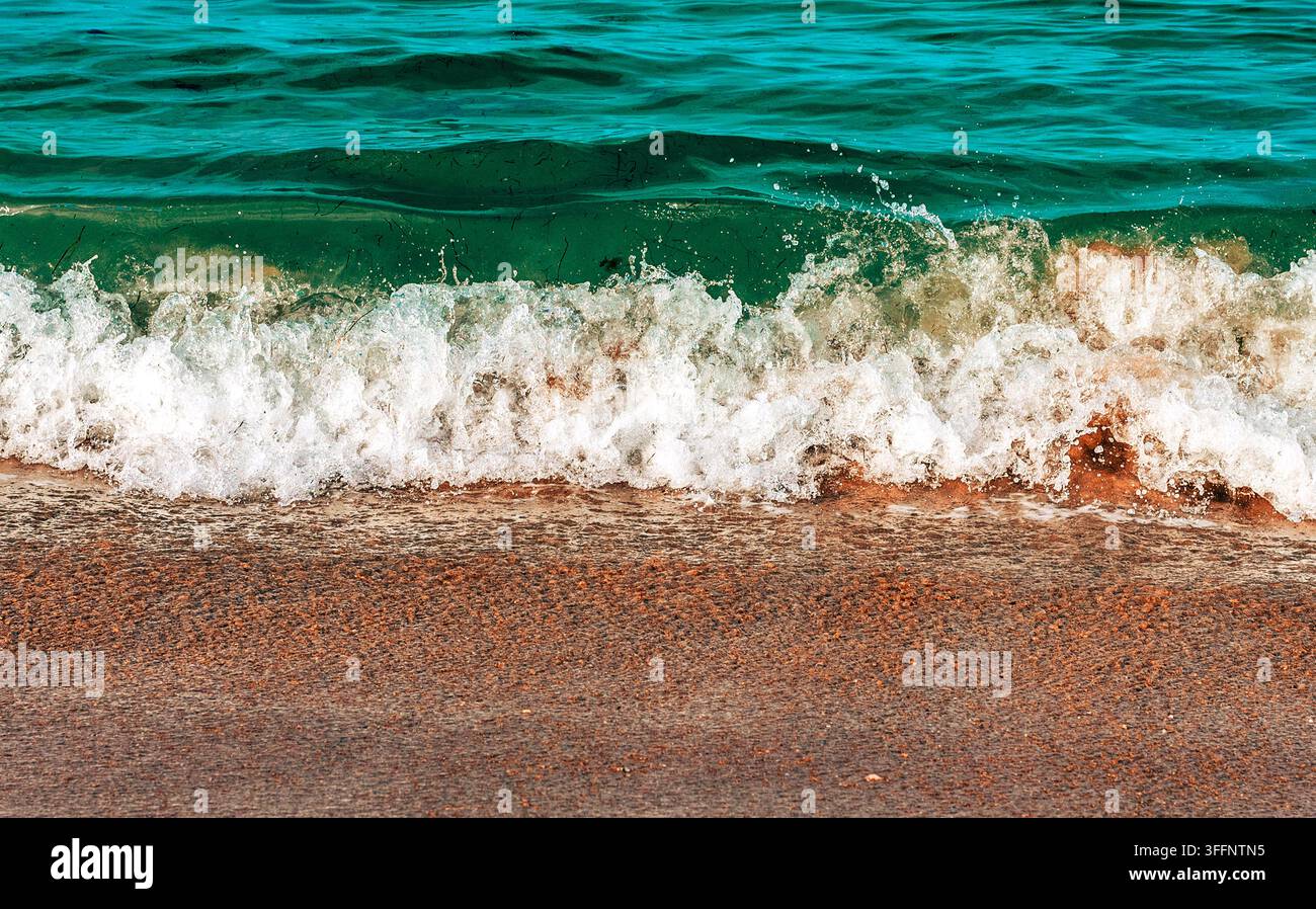 Kleine Wellen schlagen auf dem Sandstrand Stockfoto