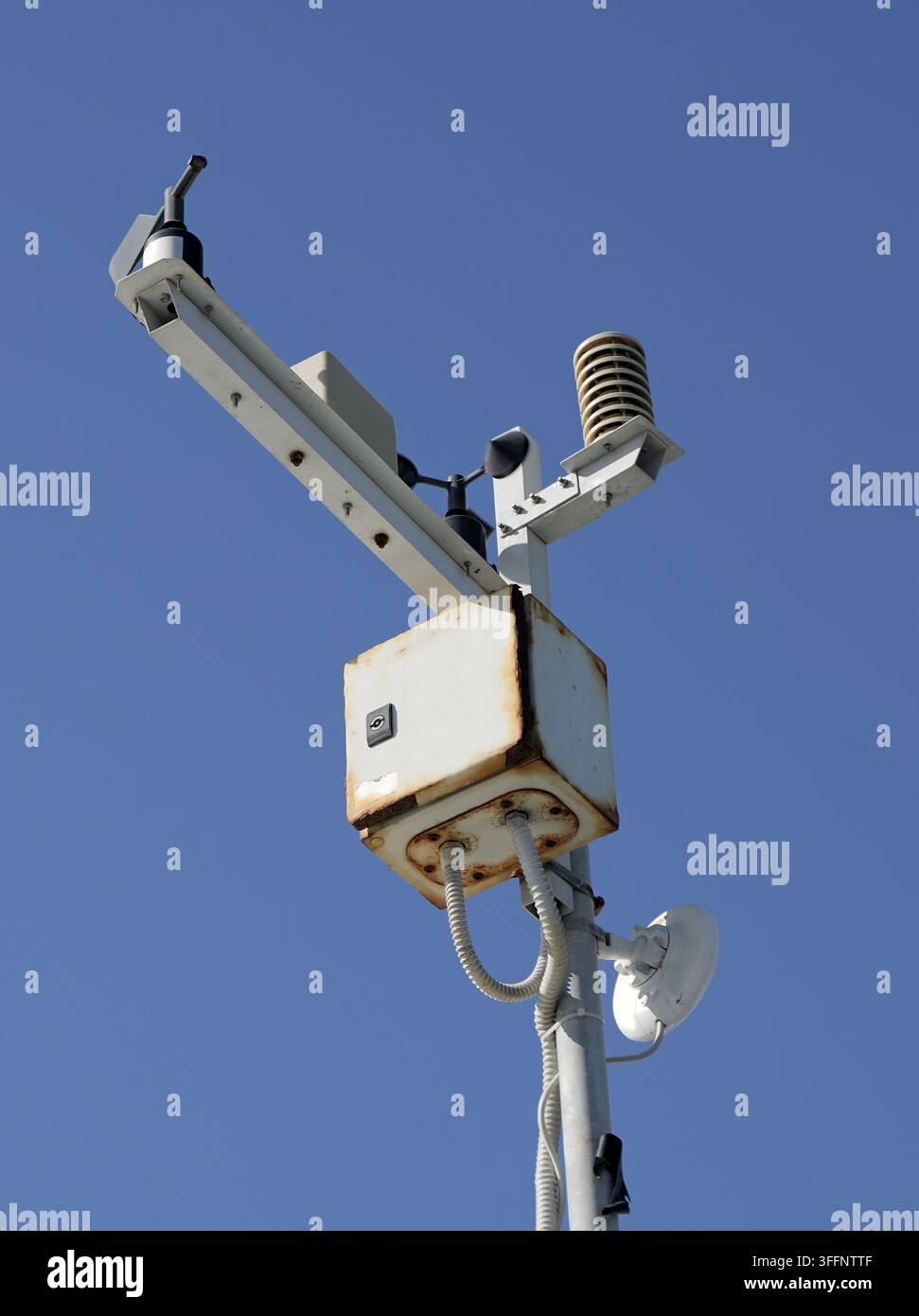 Automatische Wetterstation mit Anemometer, geschützter Thermometer und Regenmesser, die auf einem Mast montiert sind, die präzise meteorologische Messungen unterfangen Stockfoto