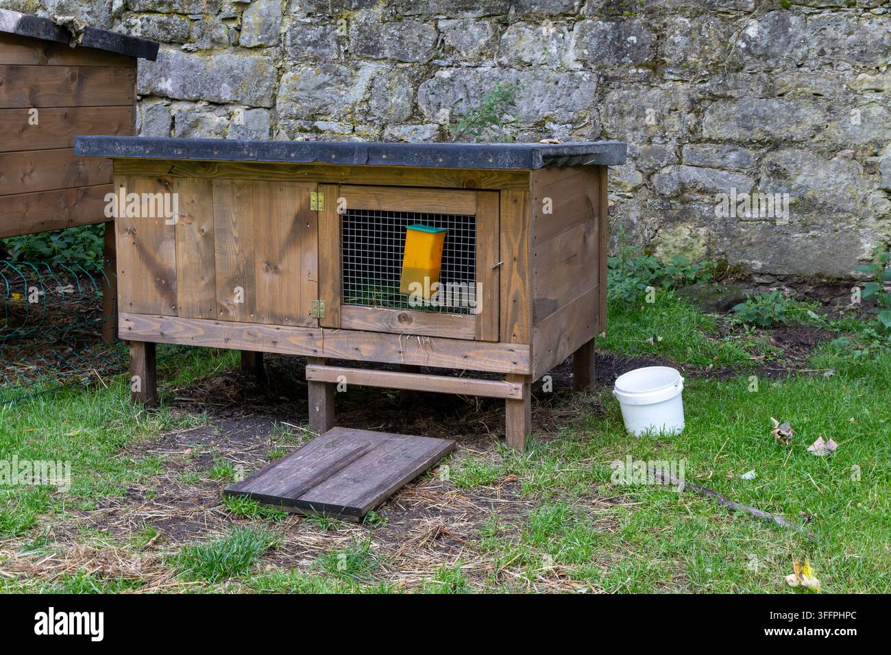 Holzkaninchenstall steht auf grünem Gras im Freien, Haustierschutz, rustikale Bauernhofumgebung. Stockfoto